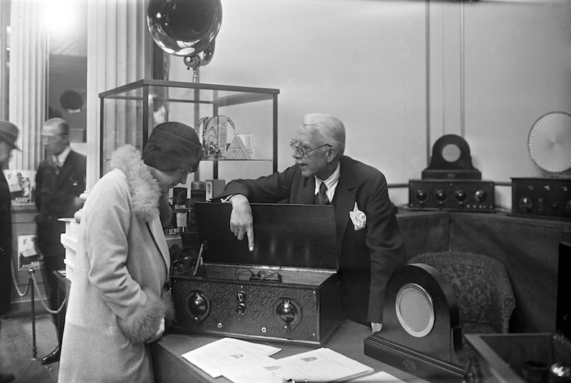 Radioen blev hurtigt et udbredt medie i Danmark fra de første amatørradioers prøveudsendelser i starten af 1920″erne til Statsradiofoniens monopolisering i 1926. Overalt i landet skød radiosendemaster op i landskabet og i 1940 havde 80% af alle danske husstande et radioapparat. Her fra radioudstilling i 1927. Foto/tekst: Holger Damgaard/Ritzau Scanpix.